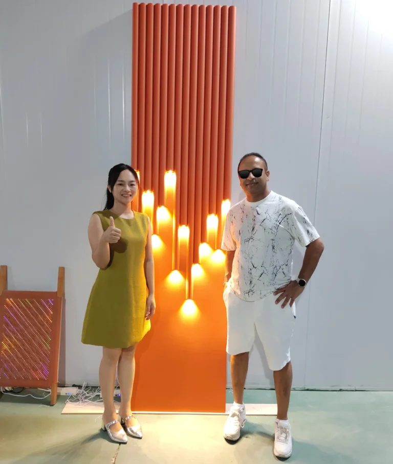 Saipin Decor team presenting a custom 3D illuminated architectural wall panel prototype to an international client during a factory tour.