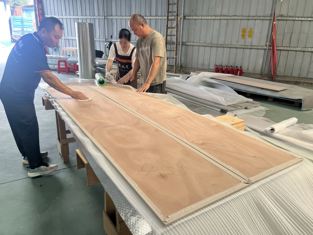 Saipin Decor factory workers applying multi-layered protective packaging to custom upholstered wall panels for international shipping.
