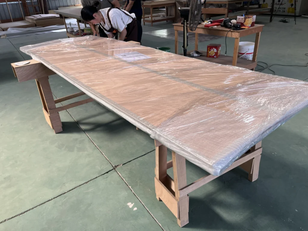 Saipin Decor factory workers applying multi-layered protective packaging to custom upholstered wall panels for international shipping.