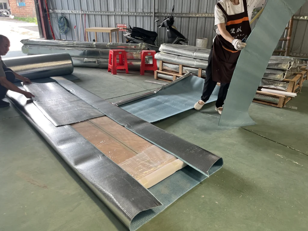 Saipin Decor factory workers applying multi-layered protective packaging to custom upholstered wall panels for international shipping.
