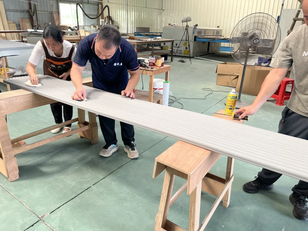 Saipin Decor factory workers applying multi-layered protective packaging to custom upholstered wall panels for international shipping.