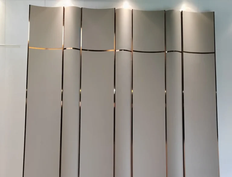 factory production floor showing Saipin Decor's bespoke 3D curved upholstered wall panels in matte taupe, featuring flawless integration of straight vertical and wavy horizontal brass metal inlays.