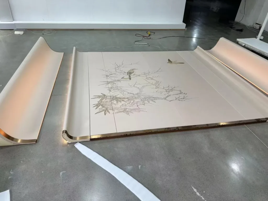 Factory floor assembly of a bespoke curved wall panel with integrated LED backlighting and gold accents by Saipin Decor.